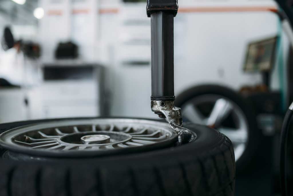 A mechanic repairs a tire, demonstrating skill and focus in a well-equipped workshop environment.